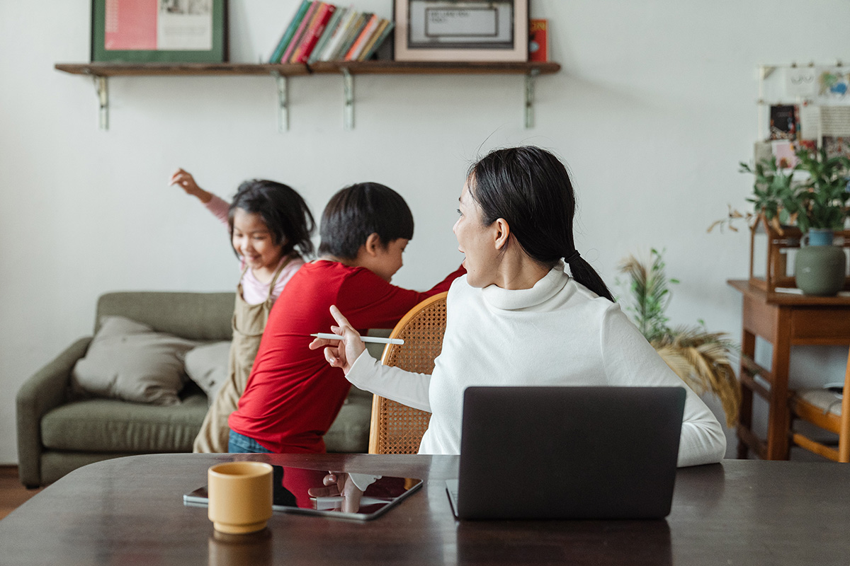 A mother manages her finances while her children play in the background